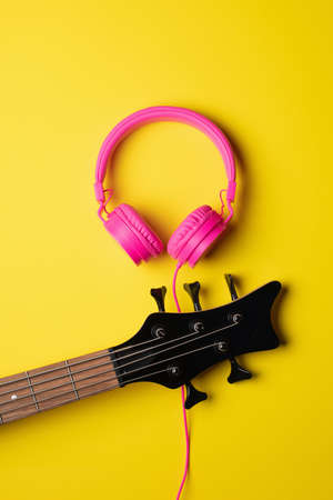 headstock of a five string guitar next to a pair of pink headsets, yellow vertical cutoutの写真素材