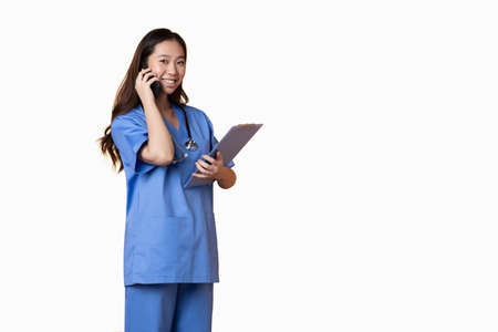 Studio photo with white background of a doctor talking to the mobile while holding a folderの写真素材