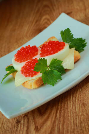 Toast with caviar, egg and cheese on a dishの写真素材