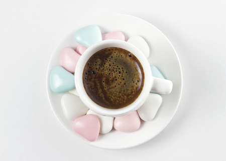 coffee cup with colorful sweets on white tableの写真素材