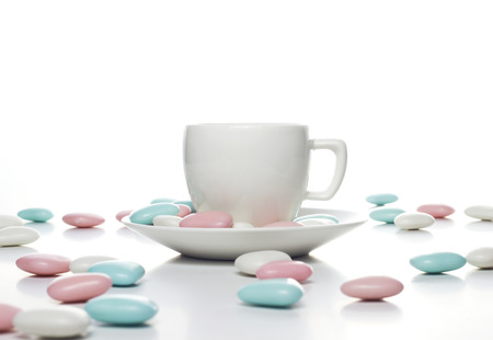 white cup with colorful sweets on tableの写真素材