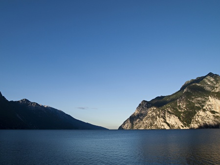 Tranquil morning at Lake Garda in northern Italy, big sky, mountains and calm water.の写真素材