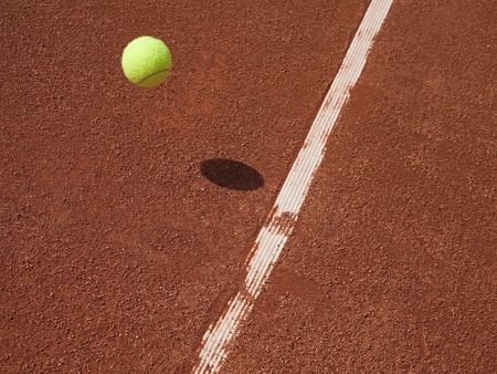 Tennis ball in air approaching the line on a red clay court.の写真素材