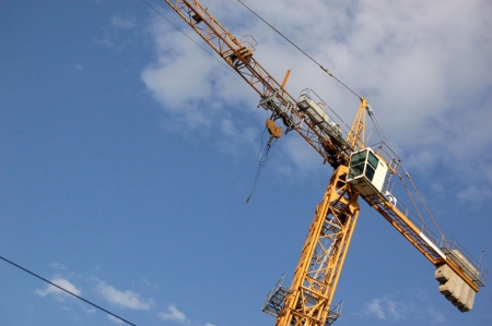yellow lifting crane over blue sky with clouds