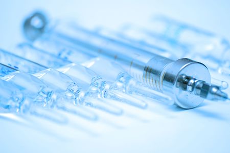 vintage glass syringe and row of medical ampullas toned in blueの写真素材