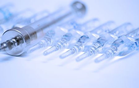 vintage glass syringe and row of medical ampullas toned in blueの写真素材