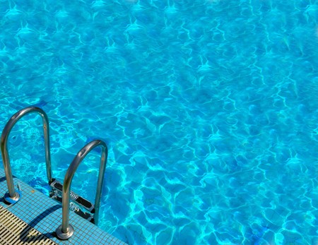 pattern of water of swimming pool with light in it and pool's stairwayの写真素材