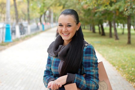 young pretty black haired girl outdoors in autumn streetの写真素材