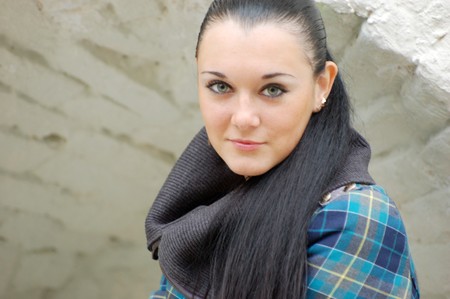 young pretty black haired girl outdoors near brick wallの写真素材