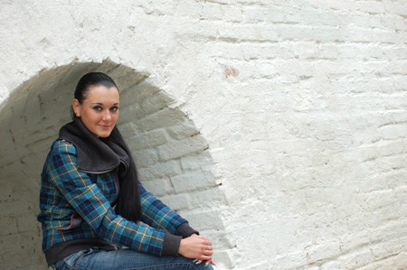young pretty black haired girl outdoors near brick wallの写真素材