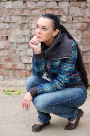 young pretty black haired girl outdoors near brick wallの写真素材