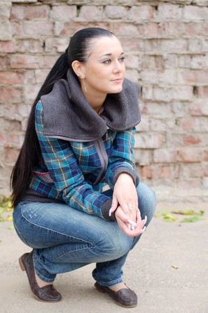 young pretty black haired girl outdoors near brick wallの写真素材
