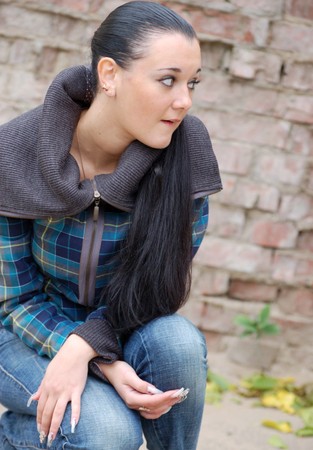 young pretty black haired girl outdoors near brick wallの写真素材