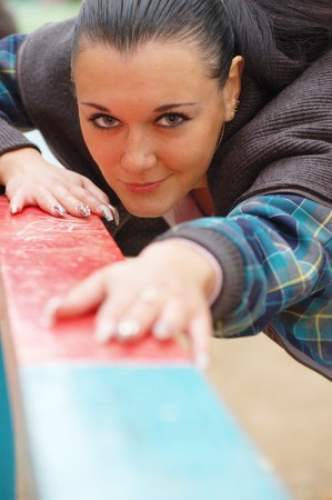 young pretty black haired girl outdoors in autumn on playgroundの写真素材