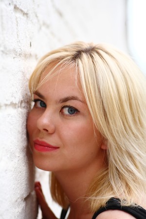 A stunningly beautiful young blond woman with bright blue eyes against wallの写真素材