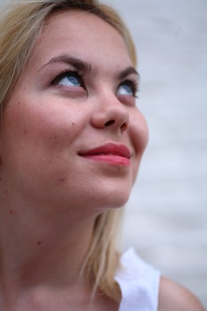 A stunningly beautiful young blond woman with bright blue eyes against wallの写真素材
