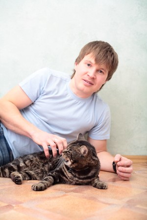 relaxed man lying on the floor with cat against wallの写真素材