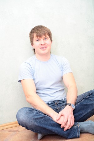 relaxed man sitting on the floor against wallの写真素材