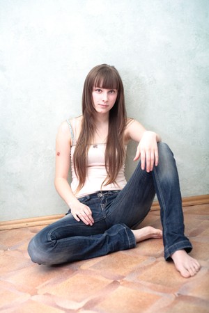 Portrait of a relaxed young woman smiling with hand on chin on sofa in living roomの写真素材