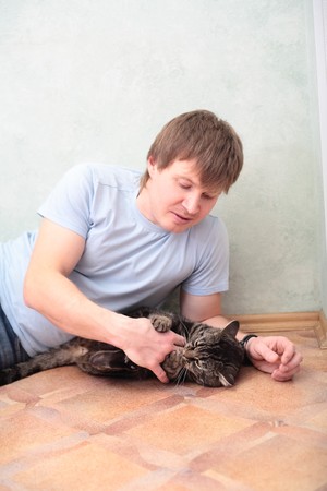 relaxed man lying on the floor with cat against wallの写真素材