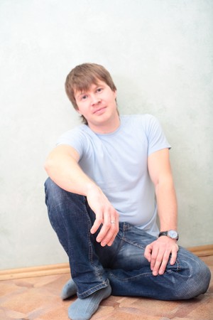 relaxed man sitting on the floor against wallの写真素材