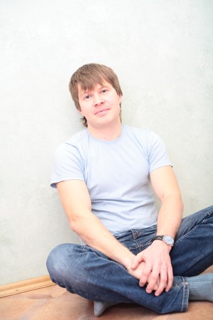 relaxed man sitting on the floor against wallの写真素材