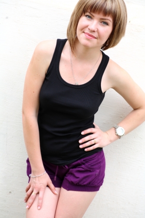 cute blonde in shorts against white wall outdoorsの写真素材