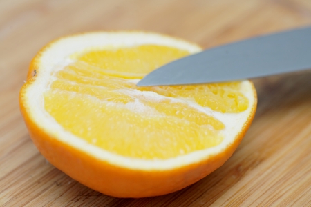 half of orange cut with knife on the board closeupの写真素材