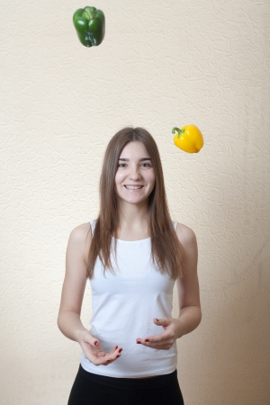 blond girl having fun with colorful peppers on the beige background. Healthy nuitrition foood conceptの写真素材