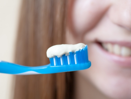 Brushing teeth. Closeup of blond woman smile brushing her teeth with toothpaste and a manual toothbrush. Beautiful caucasian model.の写真素材