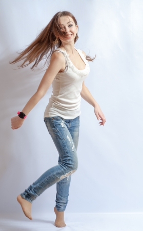 Young female dancing, fluttering on the wind hair, over white backgroundの写真素材