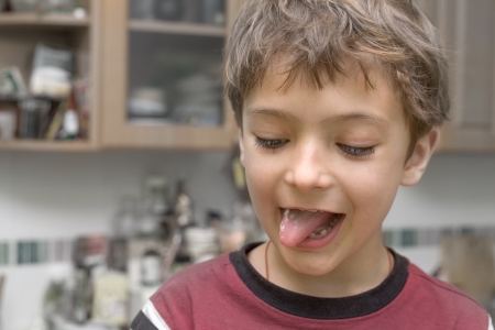 Portrait of a funny little boy making faces indoorsの写真素材
