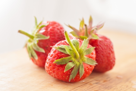 Closeup of ripe strawberries on wooden background - three strawberries on wooden tableの写真素材