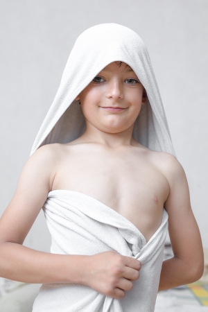 Portrait of a six year old boy with a serious expression on his face and a towel on his head torso shotの写真素材