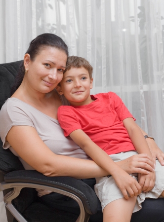 Mother kissing baby boy in red shirtの写真素材