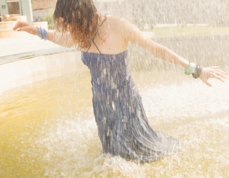 redhead women in the fountain in summertime under falling water, wet all is wet. Shot full of sunshine, Sunlit. Summer fun and enjoymentの写真素材