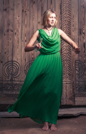 Cross processed colors romantic blond hair women in long green dress on the background of ancient wood door art posingの写真素材