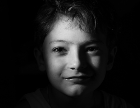 black and white shot of the boy in the dark, focused light on the head