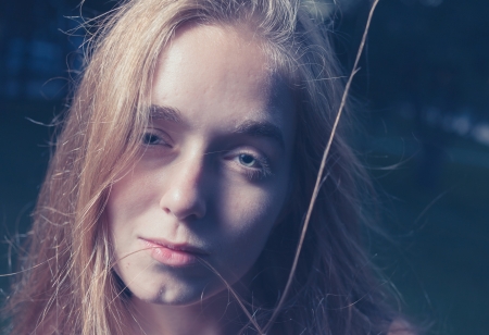 Toned image of Sad 20s female outside close-up image. Portrait of a beautiful young 20s women in the park in evening. Very closeup shot.の写真素材