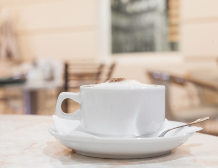 horizontal shot, cup of fresh cappuchino on the table, interior of cafe on backgroundの写真素材