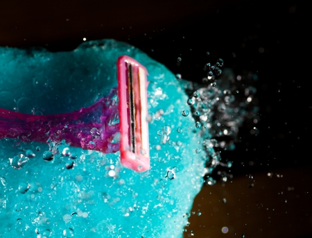 pink women shaving tool on the blue bath sponge, closeup with flying waterdropsの写真素材