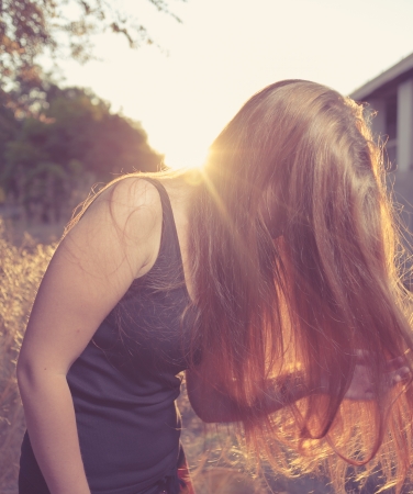Young Pretty Woman In The Autumn Park at Sunset  Backlit  Her face hidden by long blond hair  Bended pose の写真素材