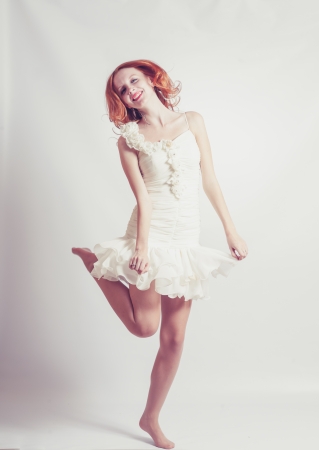 Young woman in white dress, jumps up. On gray background.の写真素材