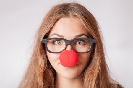 Close-up portrait of a happy 20s girl with red clown noseの写真素材