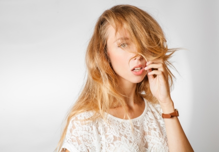 Female touch her face by hand, blond 20s female studio shot, head and shoulders imageの写真素材