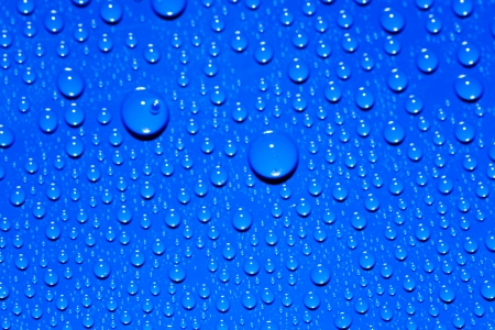 Rainbow drops on surface. Water drops on blue background