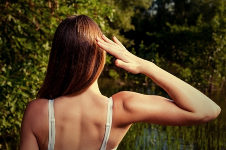 No face view of the sporty girl biceps straining. Back side of the female outdoors in summer time