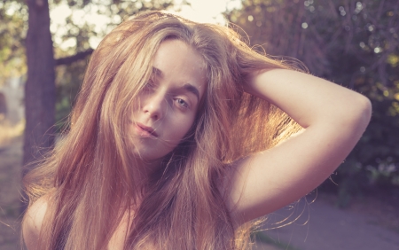 shot of long haired women touch hairs by hand outdoors