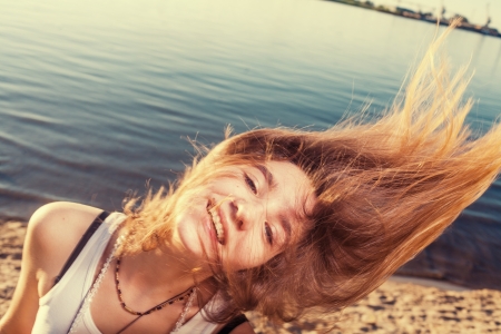 flying hair on sandy coast against waterの写真素材