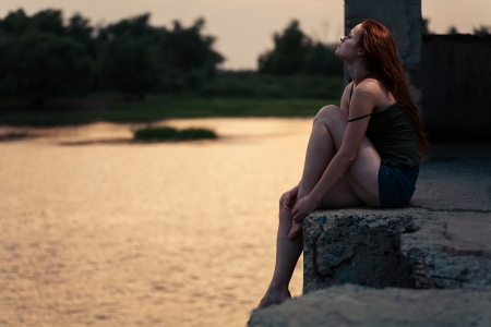 Ginger haired women looking up  Redhead women sitting near river in summertime and dreaming  Sunset lightの写真素材